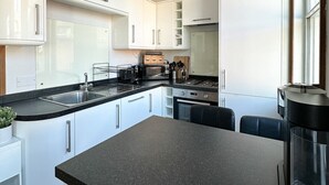 A modern kitchen with white cabinets, a black countertop, and a built-in stove. - Fulham Rooms (London)