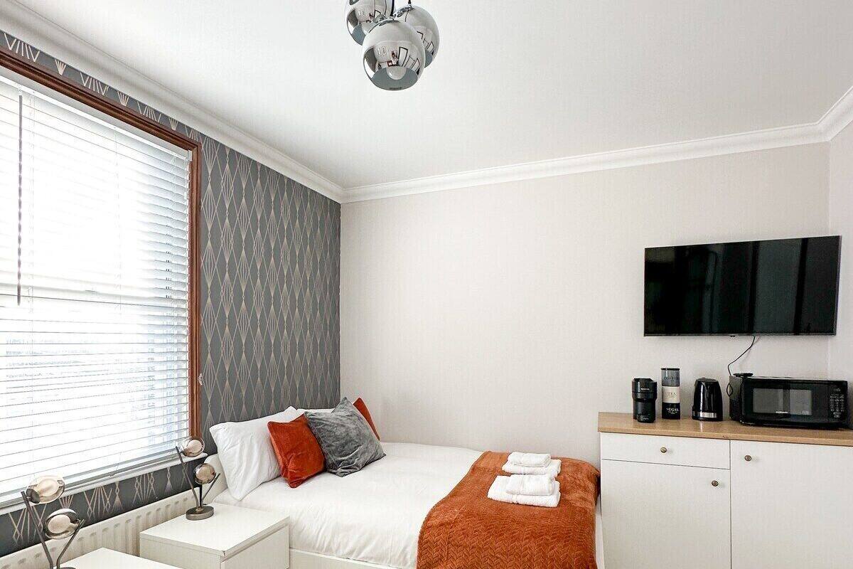 Une chambre moderne équipée d’un lit, de tables de chevet, d’un téléviseur à écran plat, d’un four à micro-ondes et d’une machine à café.