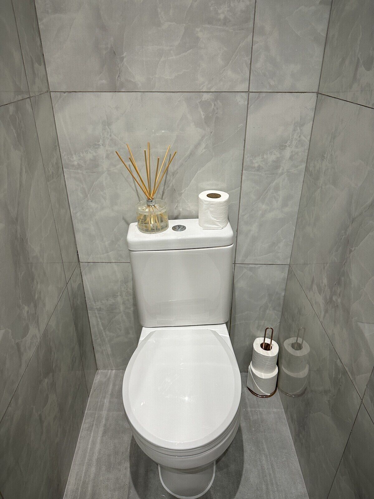 Et moderne badeværelse med toilet, bidet og to toiletpapirruller.