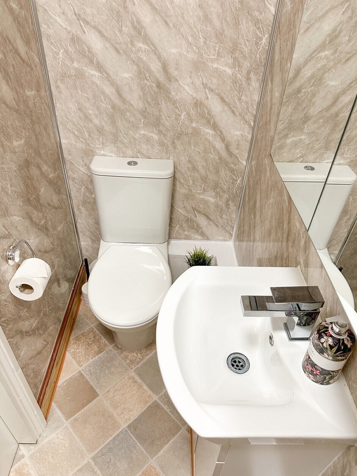 A bathroom with a toilet, sink, and mirror.