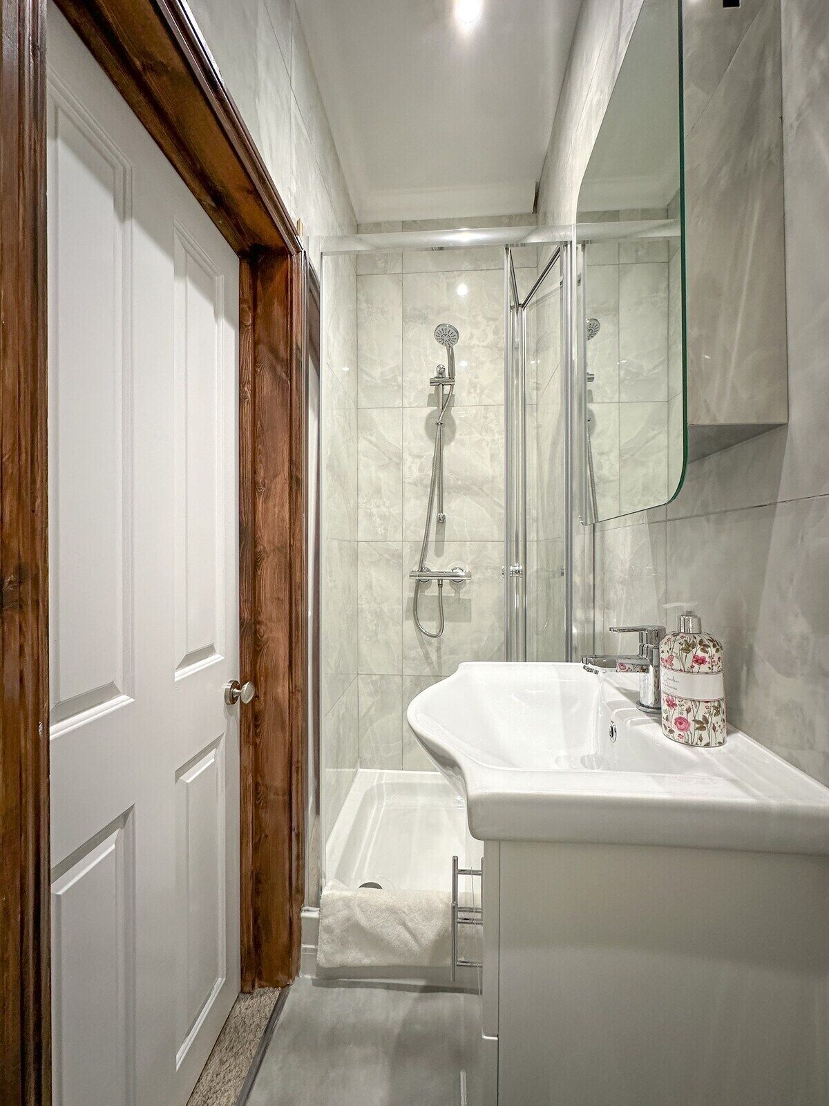 Une salle de bain avec une douche, un lavabo et un miroir.