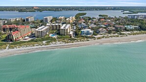 Ett flygbildsbild av ett kustområde med hotell, en strand och en vattenyta.