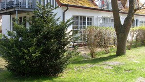 A white building with a balcony, a tree, and a grassy area. - Apartment 'Fewo Mühlenstr Mit Terrasse' with Private Terrace, Private Garden and Wi-Fi (Prerow)