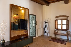 Quarto com um espelho grande, um banco, um radiador e uma janela com persianas.