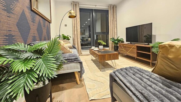 Una sala de estar moderna con sofá, mesa de centro, televisor y plantas.