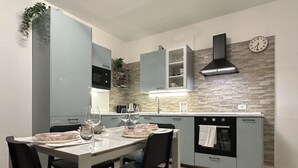 A modern kitchen with grey cabinets, a built-in oven, and a clock on the wall. - [Venice-Mestre]Design Apartment Bros#1 (Venezia)