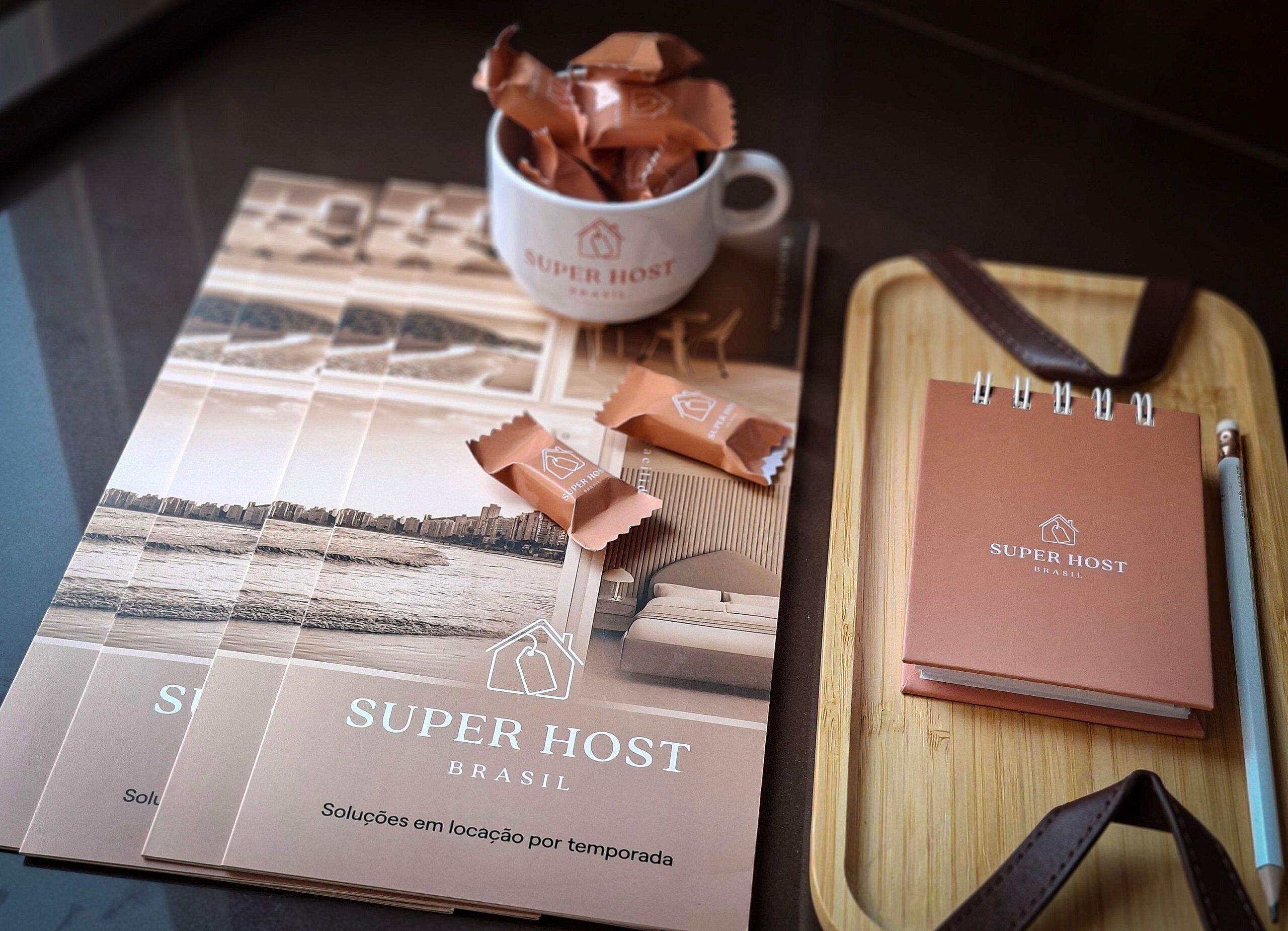 A notebook, a pen, a cup, and chocolate bars on a table.