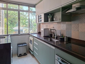 A modern kitchen with a window, stainless steel appliances, and patterned backsplash. - SHB • 3 min from the beach | Central | Biquinha (São Vicente)