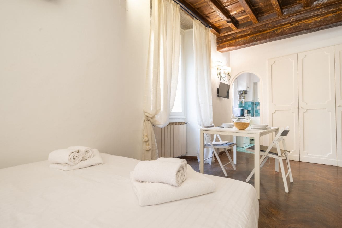 A bedroom with a bed, a table with a bowl, and a chair.