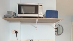 A compact kitchen with a built-in microwave, a sink, and a kettle. - Camden Rooms (London)