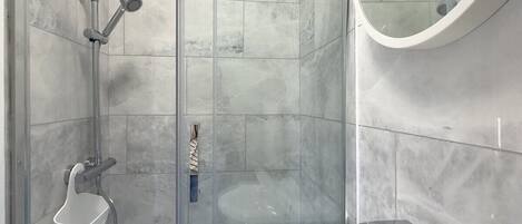 Une salle de bain moderne avec une douche à parois de verre, un lavabo blanc et un grand miroir.
