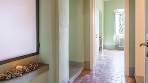 A hallway with a window, a door, and a staircase leading to another room. - Appartamento delle Logge (Cortona)