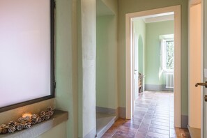 Um corredor com janela, porta e escada que dá para outro cômodo.