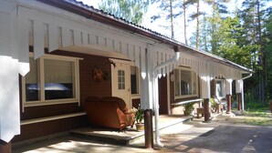 Una casa de dos pisos con un porche, un sofá marrón y una planta en maceta.