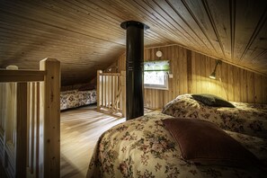 Ein gemütliches Schlafzimmer im Dachgeschoss mit Holzwänden und schrägem Dach.
