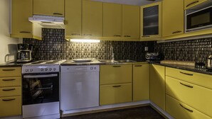 A kitchen with yellow cabinets, a white dishwasher, a stove, and a microwave. - Cabin-Garden view-Private Bathroom-Deluxe-Mökki 12,The Biggest Yell (Västerskog)