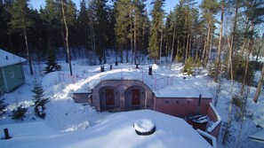 Ein mit Schnee bedecktes Gebäude mit rotem Dach, umgeben von einem Wald.