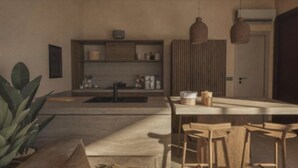 Una cocina moderna con una isla central, taburetes de madera y lámparas colgantes.