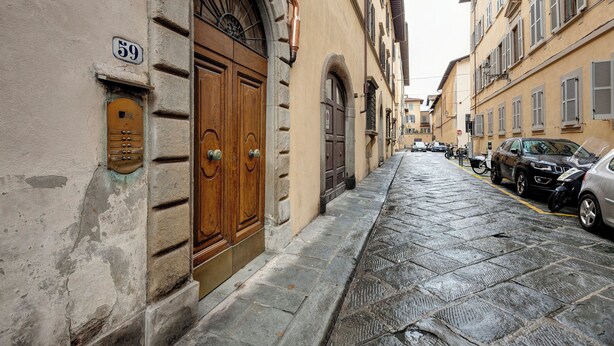 Une rue étroite, pavée de pierres, avec des portes en bois et une plaque portant le numéro 59 sur un immeuble.
