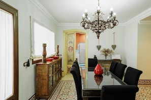 A dining area with a glass table, black chairs, a chandelier, and a wooden cabinet.