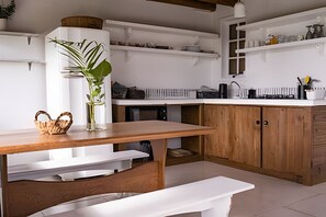 A kitchen with wooden cabinets, a white countertop, and a bench. - Casa Fluila  (Imbituba)