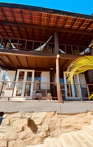 A two-story building with a wooden roof and a balcony. - Casa Fluila  (Imbituba)