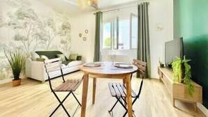Una sala moderna con una mesa de comedor, sillas, un sofá y un televisor.