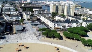 Vista aérea de un pueblo costero con playa, edificios y un puerto deportivo.
