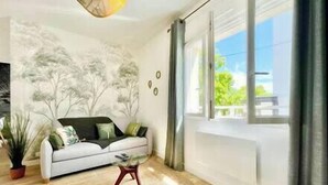 Una sala de estar moderna con un sofá blanco, una mesa de centro y un mural de árboles en la pared.