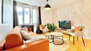 A modern living room with a sofa, armchairs, a coffee table, and a television.