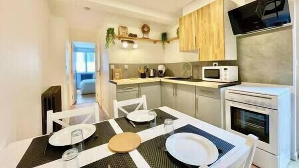 A compact kitchen with a dining area, equipped with a microwave, oven, and a small sink.