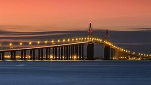 A long bridge with lights, spanning across a body of water.