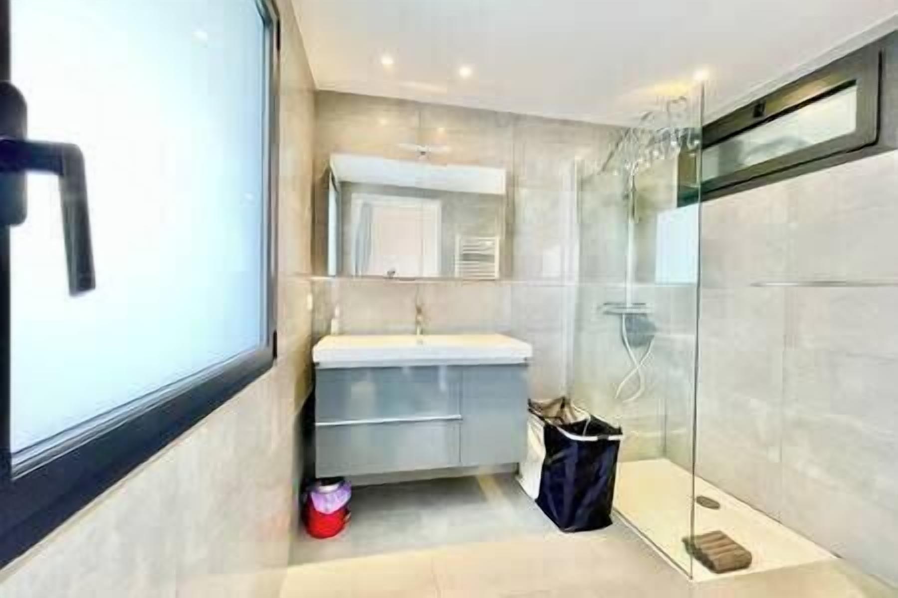 Une salle de bain moderne avec une douche à parois de verre, un lavabo blanc et un miroir au-dessus.