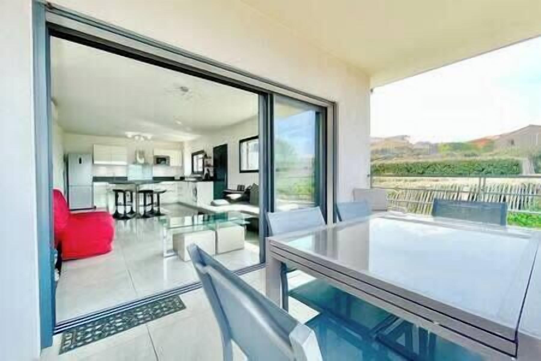 Un apartamento moderno con balcón de cristal, cocina y comedor.