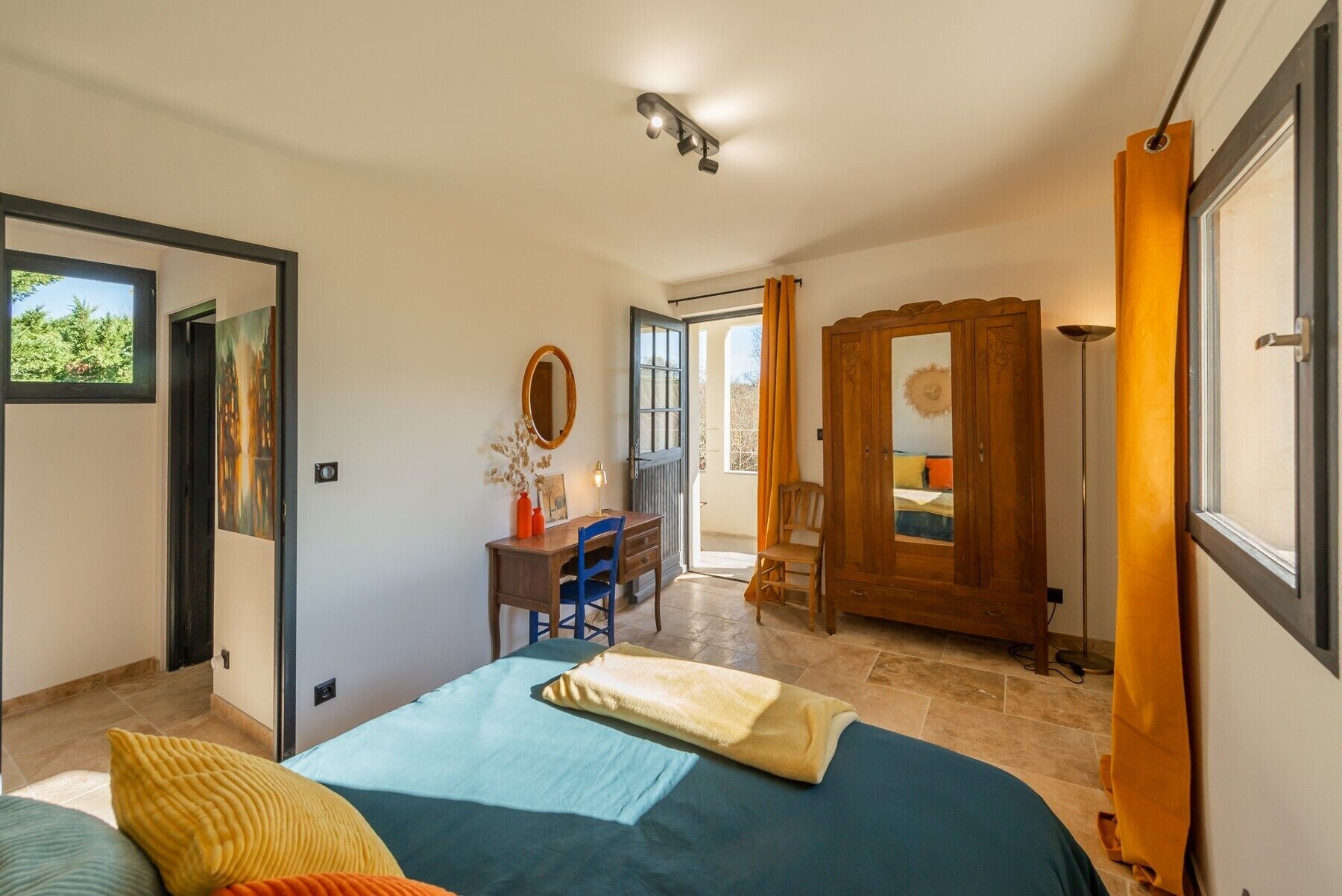 Un dormitorio con cama, escritorio, silla, espejo y armario.