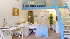 A compact bedroom with a bunk bed, a desk with chairs, a small dining table, and a staircase. - Bright studio close to the beach in Roquebrune (Roquebrune-sur-Argens)