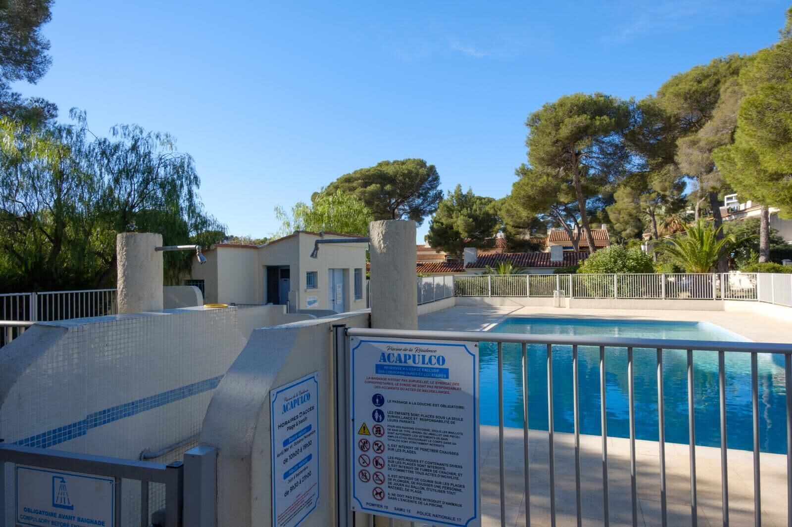 A swimming pool area with a sign indicating 'ACAPULCO' and safety instructions.