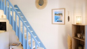 A staircase with blue railings, a framed coastal landscape picture, a decorative mirror, and a shelf with candles and a lamp. - Bright studio close to the beach in Roquebrune (Roquebrune-sur-Argens)