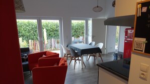 Un comedor con una mesa y sillas, un sofá rojo y vistas al exterior.