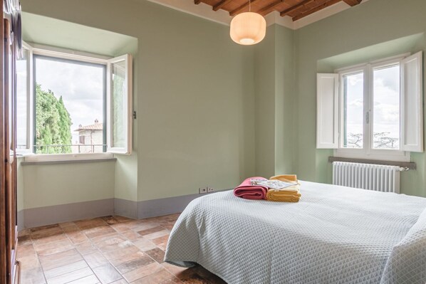 Una camera da letto con un letto, una finestra, un termosifone e una lampada a soffitto.