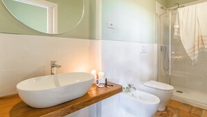 Ein Badezimmer mit einem großen, ovalen Waschbecken, einer Toilette und einer Dusche.