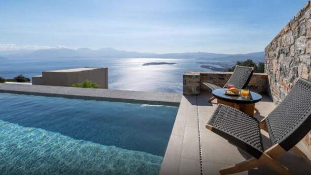 Un espace aménagé au bord de la piscine, offrant une vue sur la mer et les montagnes.