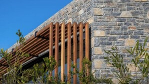 Un bâtiment en pierre doté d’une structure de pergola en bois.