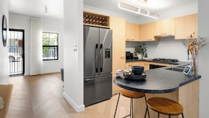 Une cuisine moderne dotée d’un réfrigérateur en acier inoxydable, de meubles en bois, d’un plan de travail en marbre et d’une cuisinière encastrée.