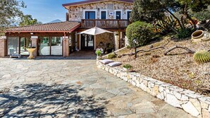 A stone building with a red roof, a covered patio, and a landscaped garden with cacti. - Room 'Mirto' with Mountain View, Wi-Fi and Air Conditioning (Uta)