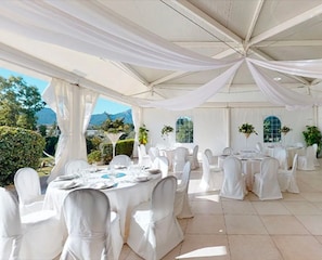 An outdoor tented dining area with white tablecloths and chairs, surrounded by greenery and a mountain view. - Room 'Mirto' with Mountain View, Wi-Fi and Air Conditioning (Uta)