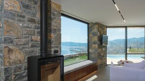 Quarto moderno com parede de pedra, uma janela ampla e uma lareira a lenha.