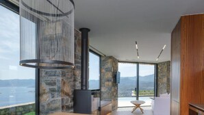 Cozinha moderna com parede de pedra, mesa de jantar de madeira e vista para as montanhas.
