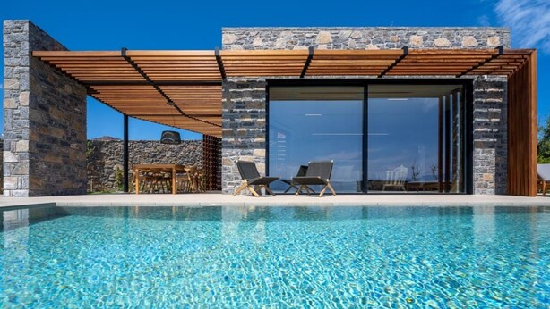 A modern poolside area with a clear pool, wooden pergola, stone walls, and two lounge chairs. - Villa Narethea, Divine Sea Views, Private Pool, Furnished Terrace, Crete (Crete)