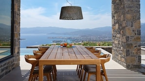A wooden table with chairs, a hanging lamp, and a view of a coastal landscape with mountains in the background. - Villa Narethea, Divine Sea Views, Private Pool, Furnished Terrace, Crete (Crete)